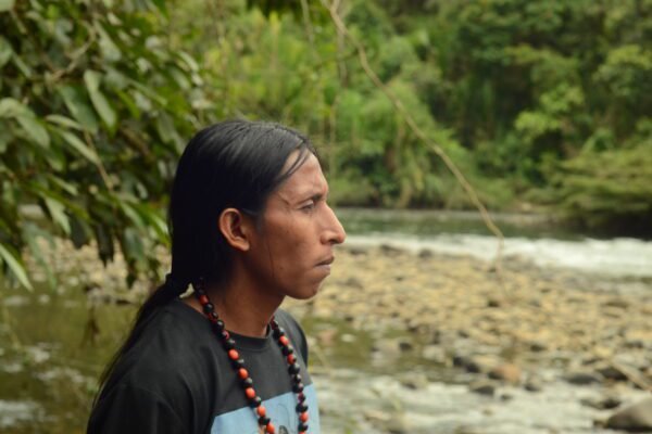 Joven de un pueblo originario de la amazonía de Ecuador mirando río contaminado